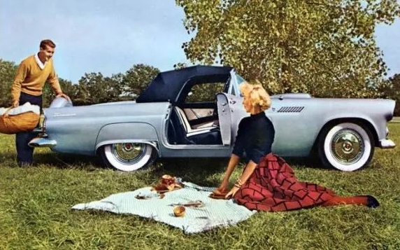 1956 Thunderbird in Thunderbird Gray Metallic - note standard rear spare tire carrier and front cowl vent (corner is barely visible over woman's left shoulder) Image: 1956 Ford Thunderbird